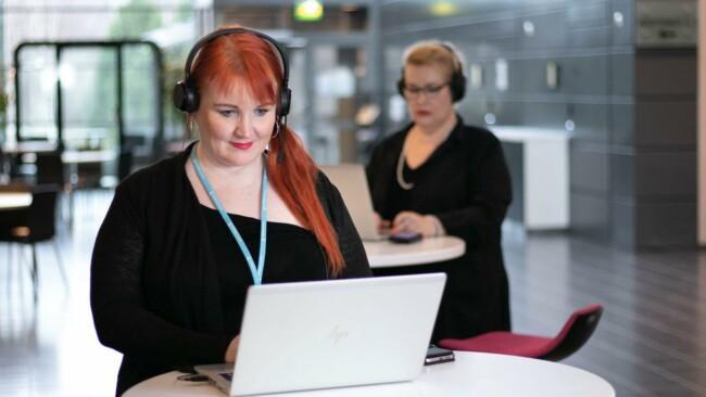 Kaksi naista kuulokkeet päässä opiskelee verkko-opinnoissa.
