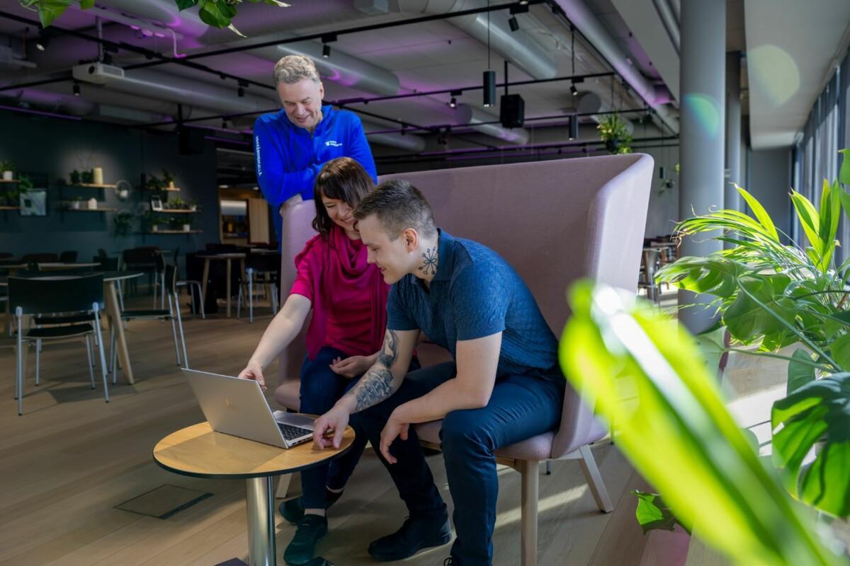 Nainen esittelee kahdelle miehelle kannettavalta tietokoneelta Suomen Yrittäjäopiston hakua