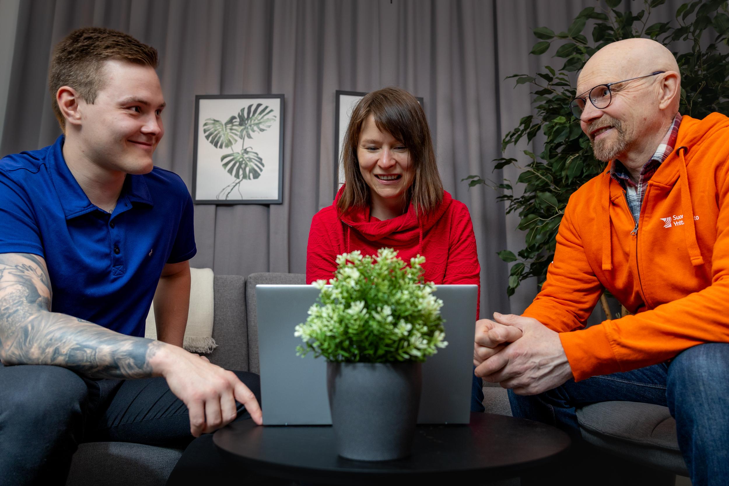 Kolme hymyilevää henkilöä istuu sohvalla läppärin edessä ja katsoo Suomen Yrittäjäopiston maatalouden koulutusmahdollisuuksia.