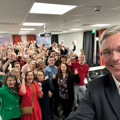 Rehtori ottaa selfien ja taustalla Suomen Yrittäjäopiston henkilökunta.